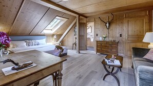 Ein geräumiges Schlafzimmer im Loft-Stil mit schrägem Dach, Dachfenster, Holzmöbeln und einer Dekoration mit Hirschgeweih.