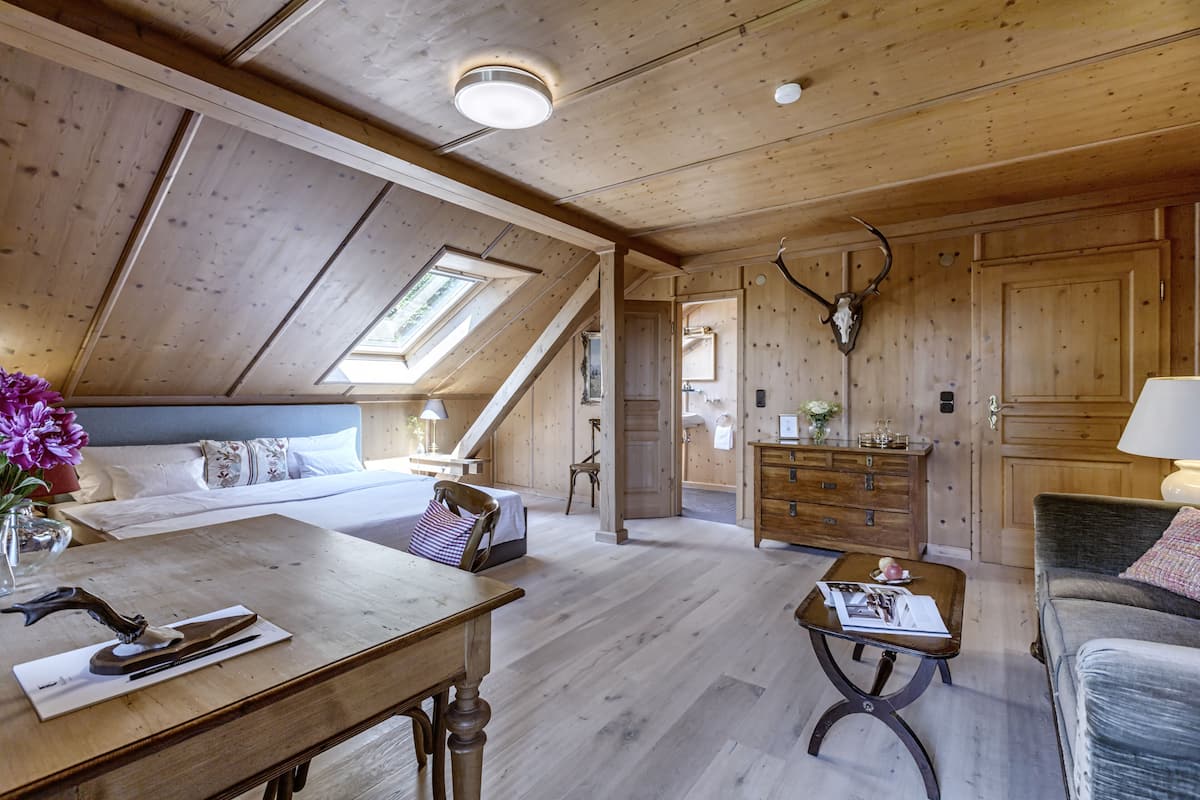 Une chambre spacieuse aménagée en mezzanine, avec un plafond en pente, une lucarne, des meubles en bois et une décoration représentant une tête de cerf.
