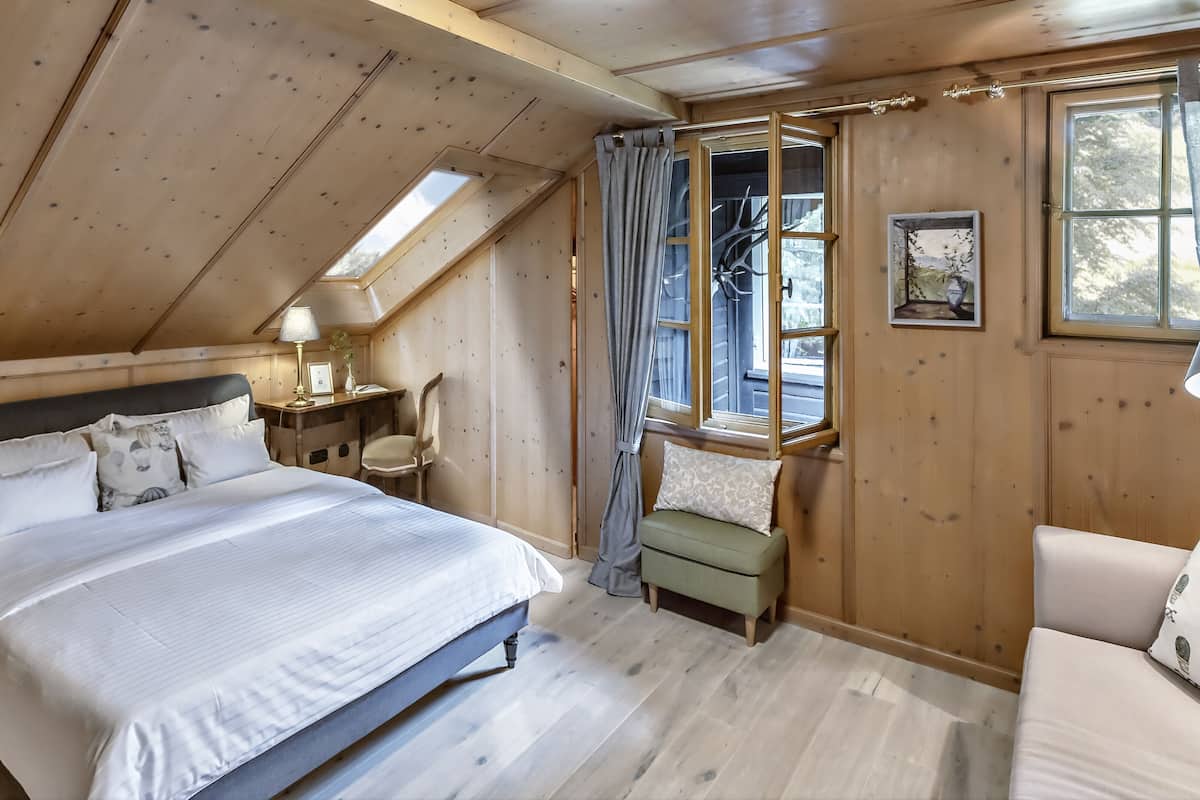 Une chambre confortable avec un grand lit, un bureau, une chaise et une fenêtre avec des rideaux.