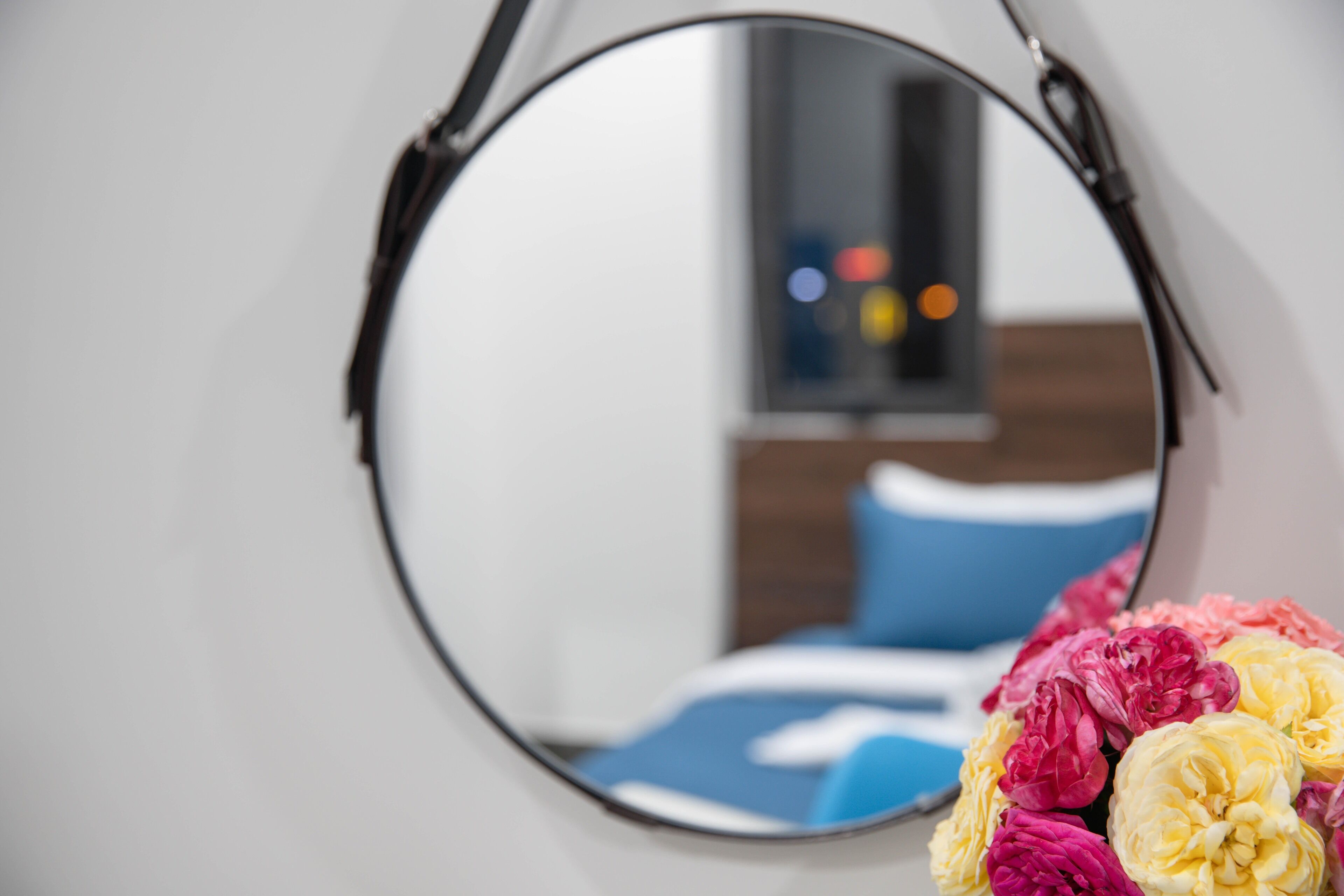 Un miroir rond avec un cadre noir, accroché à un mur blanc.