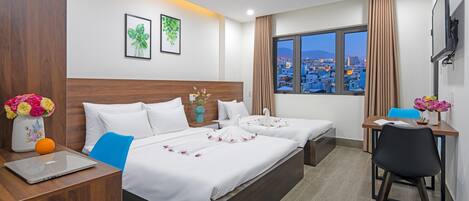Habitación de hotel con cama, escritorio, silla y vistas de la ciudad a través de una ventana.