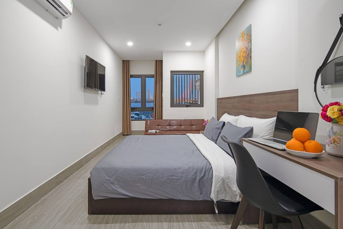 Quarto de hotel moderno com cama, escrivaninha e laptop.