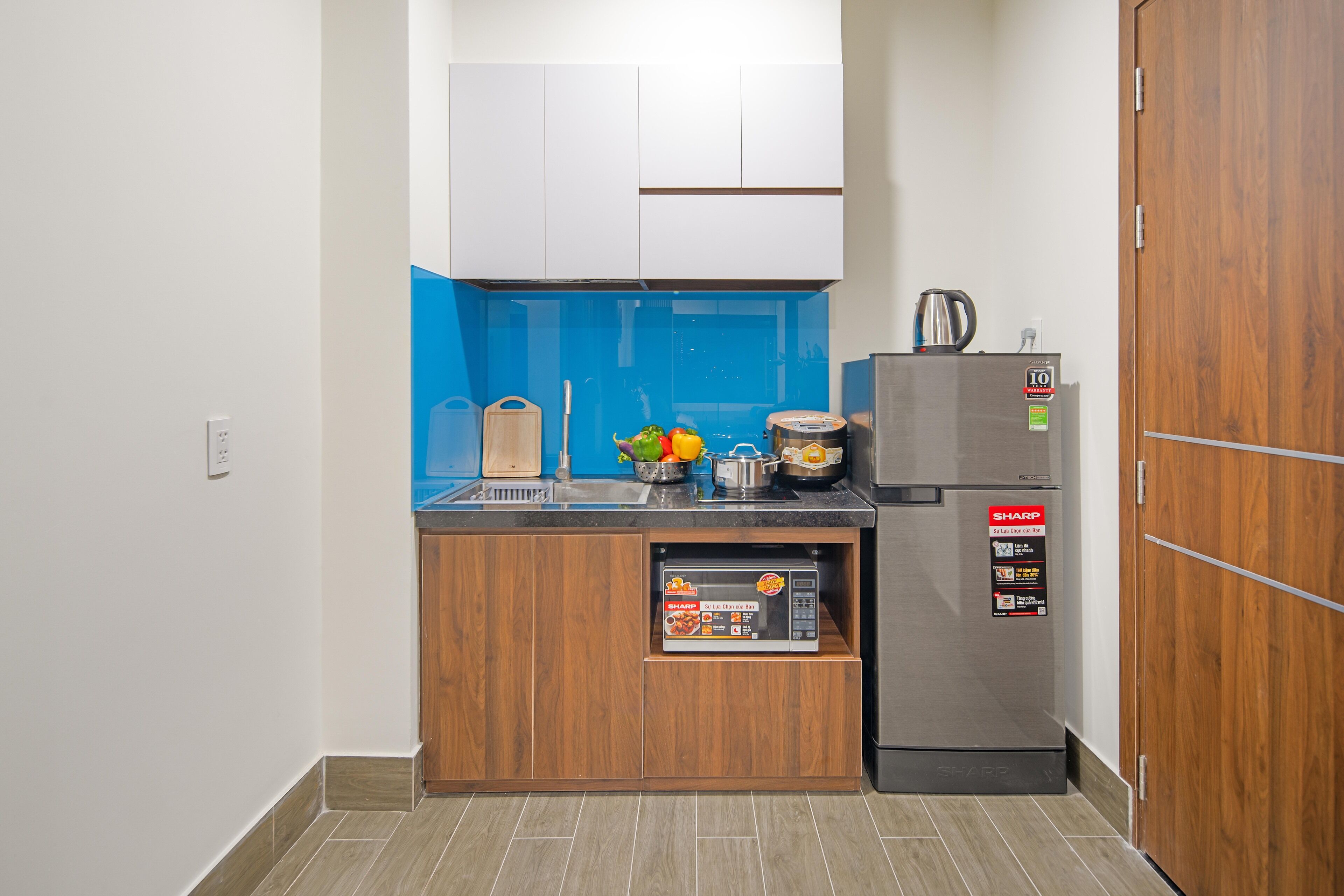 Una cocina compacta con microondas integrado, un refrigerador y un lavamanos.