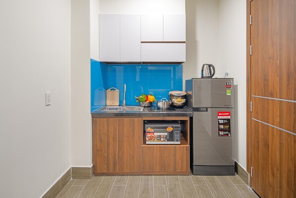 Una cocina compacta con microondas integrado, un refrigerador y un lavamanos.