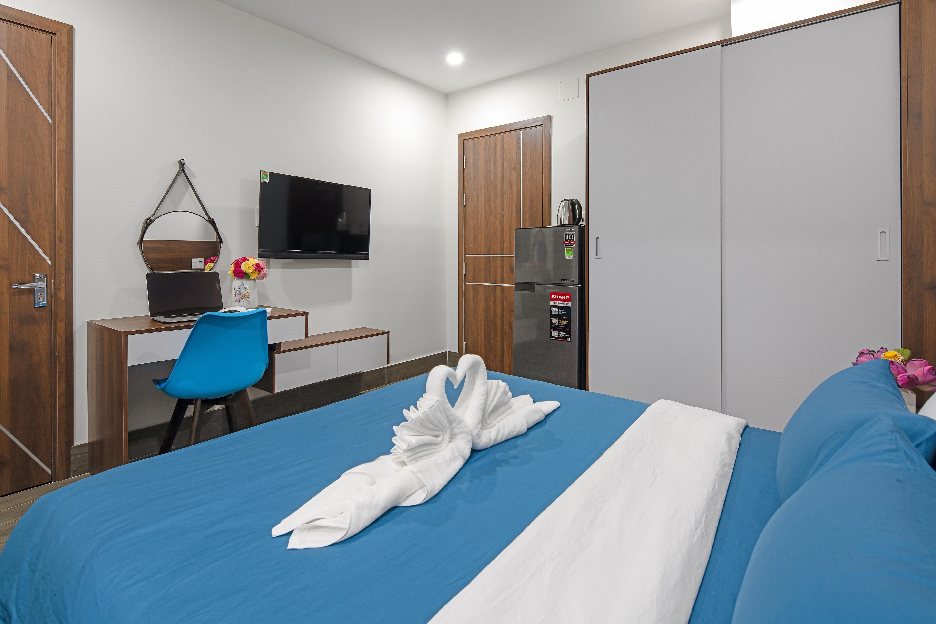 Ein Hotelzimmer mit einem Bett, einem Schreibtisch mit Stuhl, einem Fernseher, einem Kleiderschrank und einem Kühlschrank.
