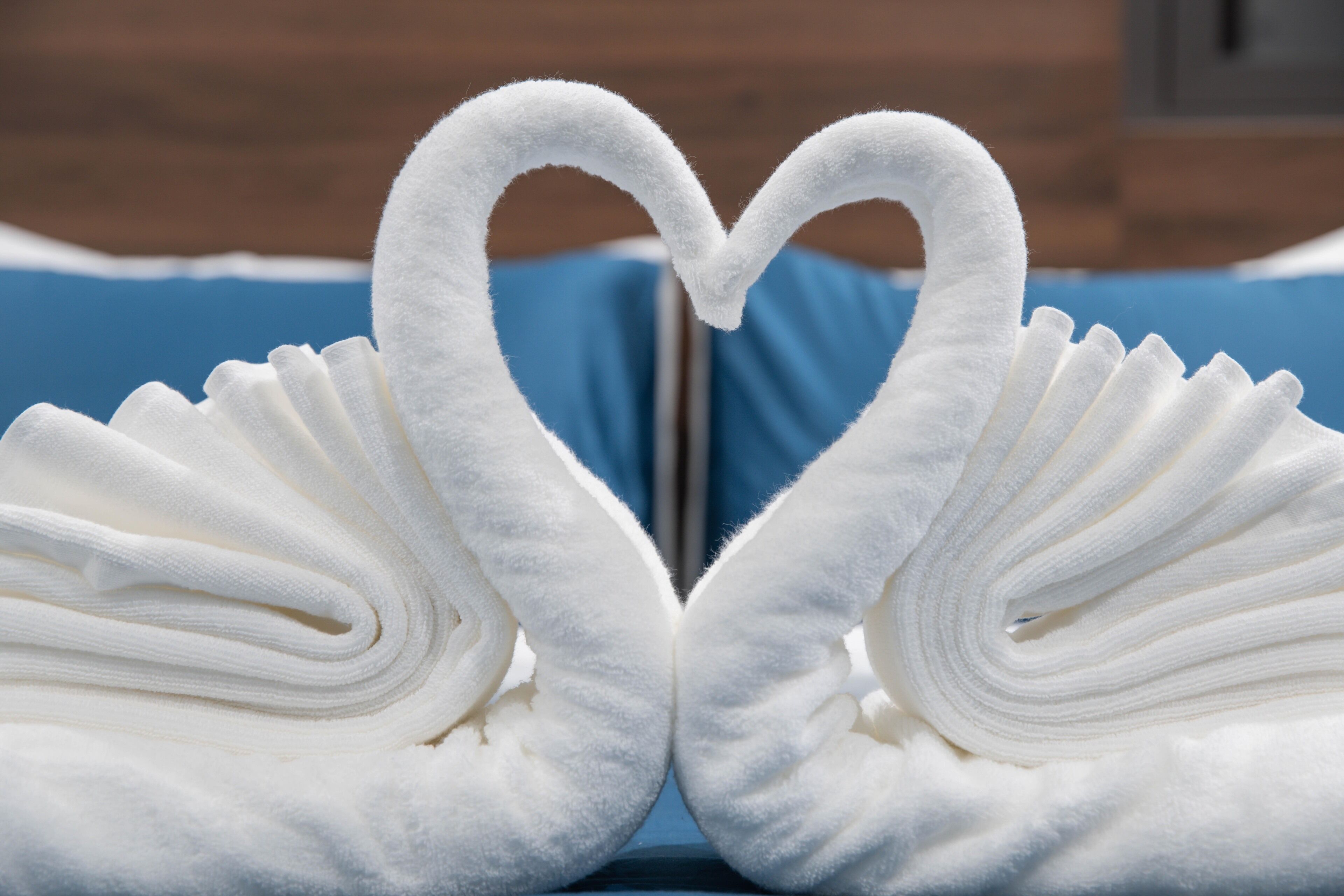 Two towels arranged in the shape of swans with a heart in the center.