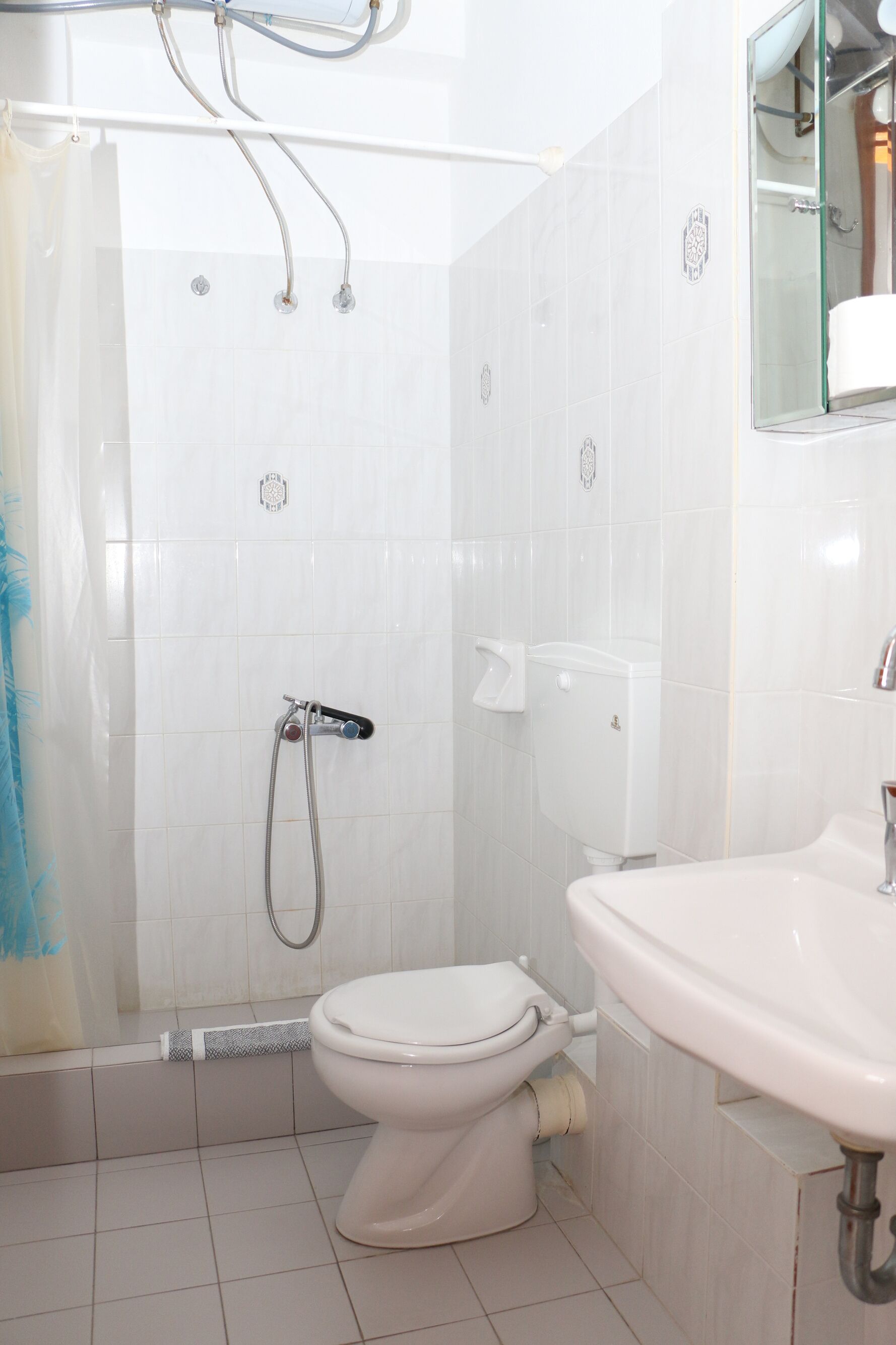 A bathroom with a toilet, shower, and sink.