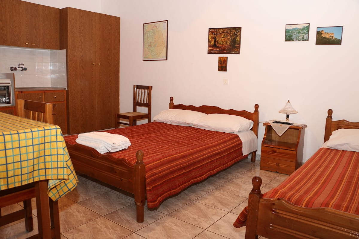 Un dormitorio con dos camas, un armario de madera, un escritorio con una silla y una mesa.
