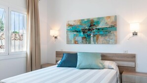 Una cama bien tendida con ropa de cama a rayas, un cabecero de madera y dos lámparas de noche.
