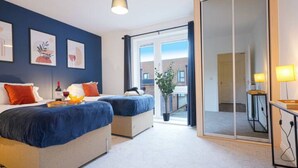 Hotellihuone, jossa on kaksi sänkyä, suuri peili, ruukkukasvi ja näkymä ulos.