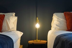 A room with two beds, a round wooden nightstand, and a single table with a lamp. - Beautiful Apartment • City Centre • Balcony • Free Parking • Fast WiFi • Smart TV • Yoko Property (Milton Keynes)