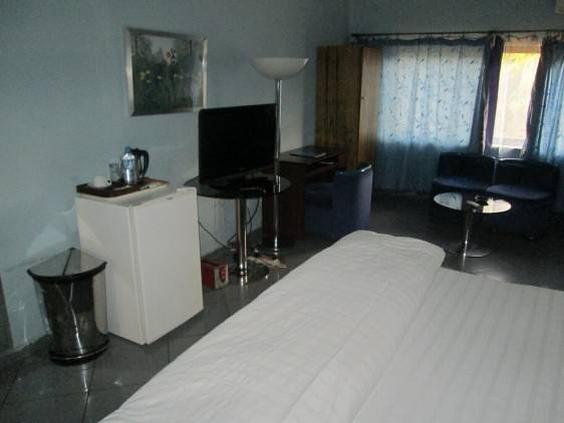 Ett hotellrum med en säng, ett skrivbord, en tv, ett litet bord och en stol.