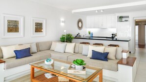A modern living room with a sofa, coffee table, and kitchen area in the background. - 14 Alamanda Resort  - Where Pure Luxury meets the Coral Sea (Palm Cove)