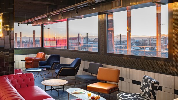 A modern lounge area with seating, a table with breakfast, and large windows offering a city view. - Eklo Hotels Clermont-Ferrand City center train station (Clermont-Ferrand)