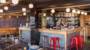 A restaurant interior with a bar area, multiple seating options, and a bartender at the bar. - Eklo Hotels Clermont-Ferrand City center train station (Clermont-Ferrand)