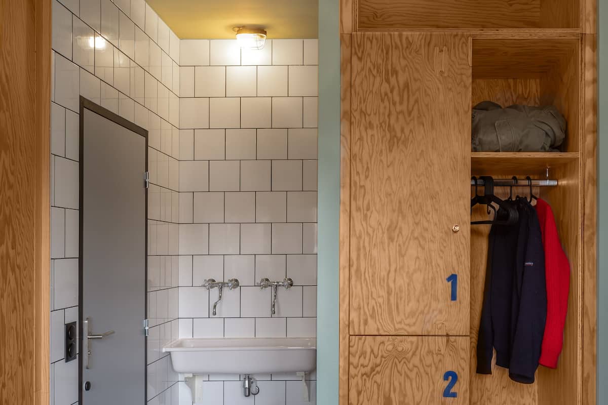 A bathroom with a wooden wardrobe, a sink, and a tiled wall.