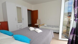 Une chambre d’hôtel avec un lit, une armoire, une chaise et une vue sur l’extérieur, visible à travers une porte vitrée.