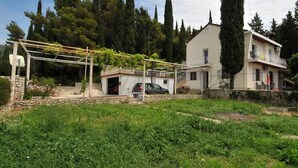 Une maison à deux étages dotée d’un balcon, d’un garage et d’un jardin agrémenté d’une pergola.