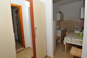 Cozinha pequena e compacta com o básico, sala de jantar com mesa e cadeiras, e piso com padrão.