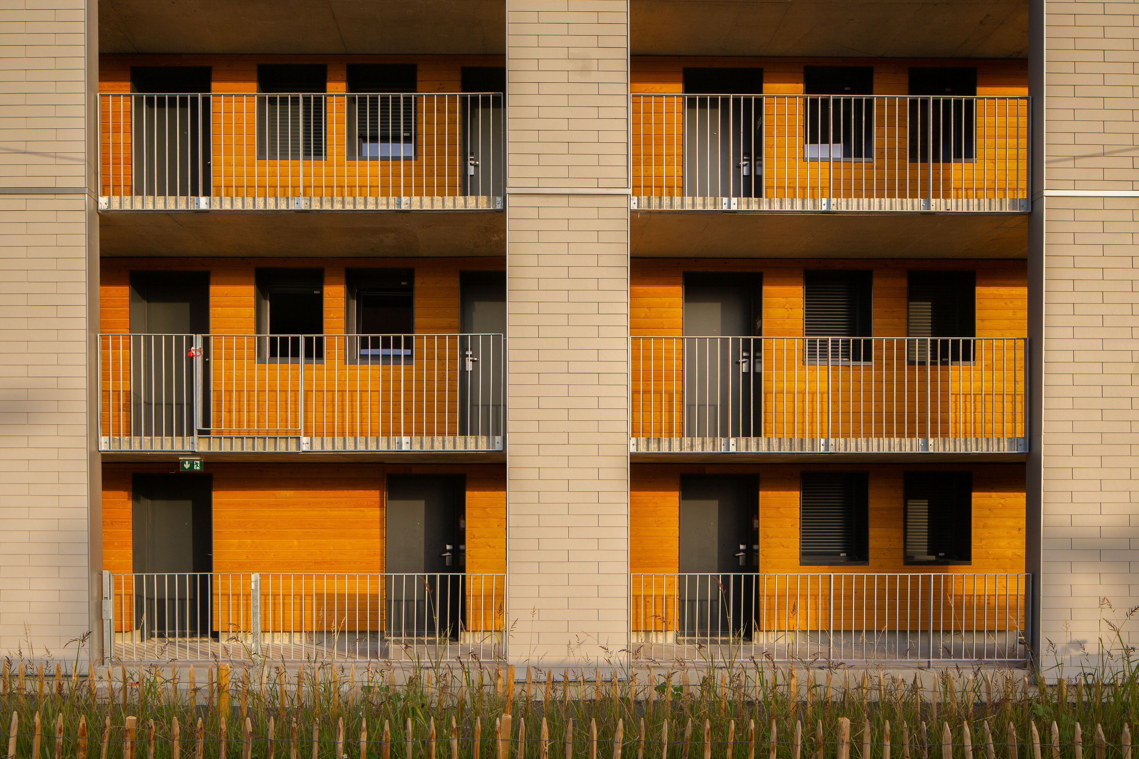 Un edificio de varios pisos con balcones, fachada de ladrillo y techo plano.