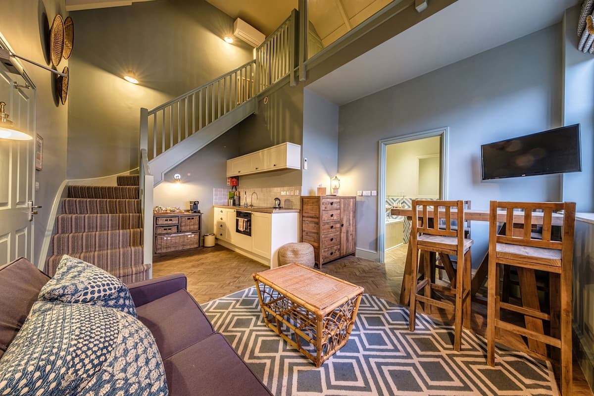 Amplia sala de estar con una escalera, una cocina y un comedor.