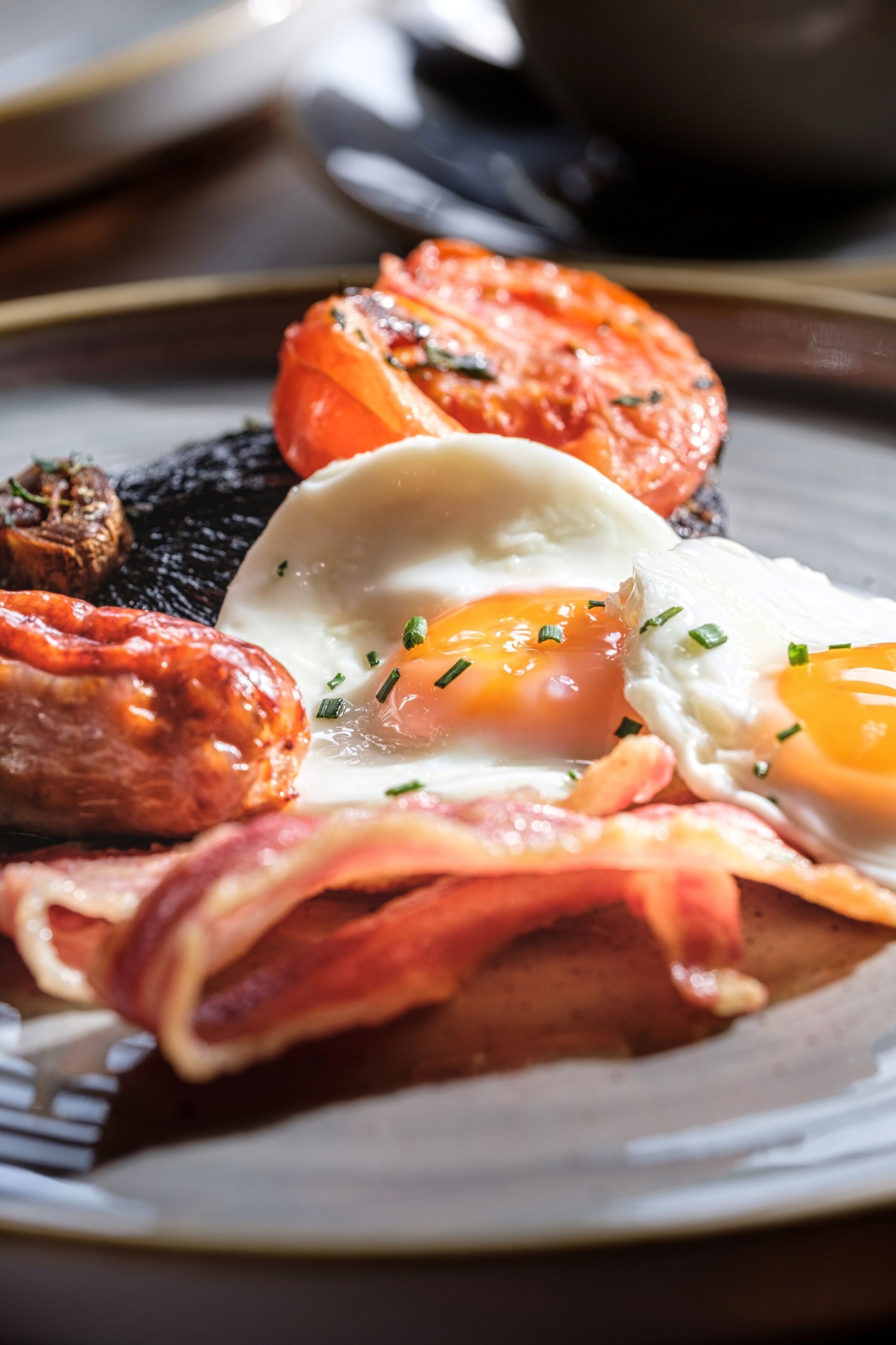 Un plato de desayuno con huevos, tocino, salchichas y tomates.