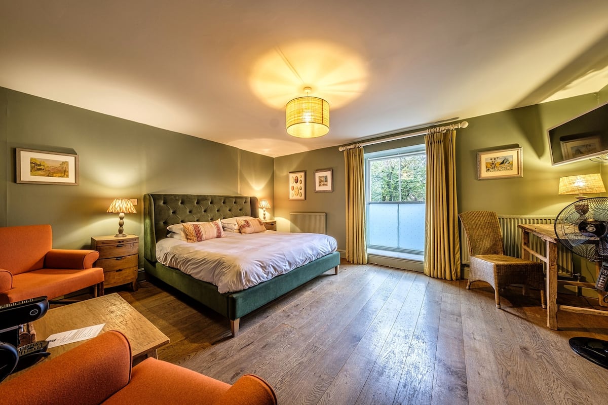 Un dormitorio con una cama grande, un escritorio, una silla y una ventana con cortinas.