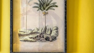 A framed botanical illustration of palm trees on a yellow wall.