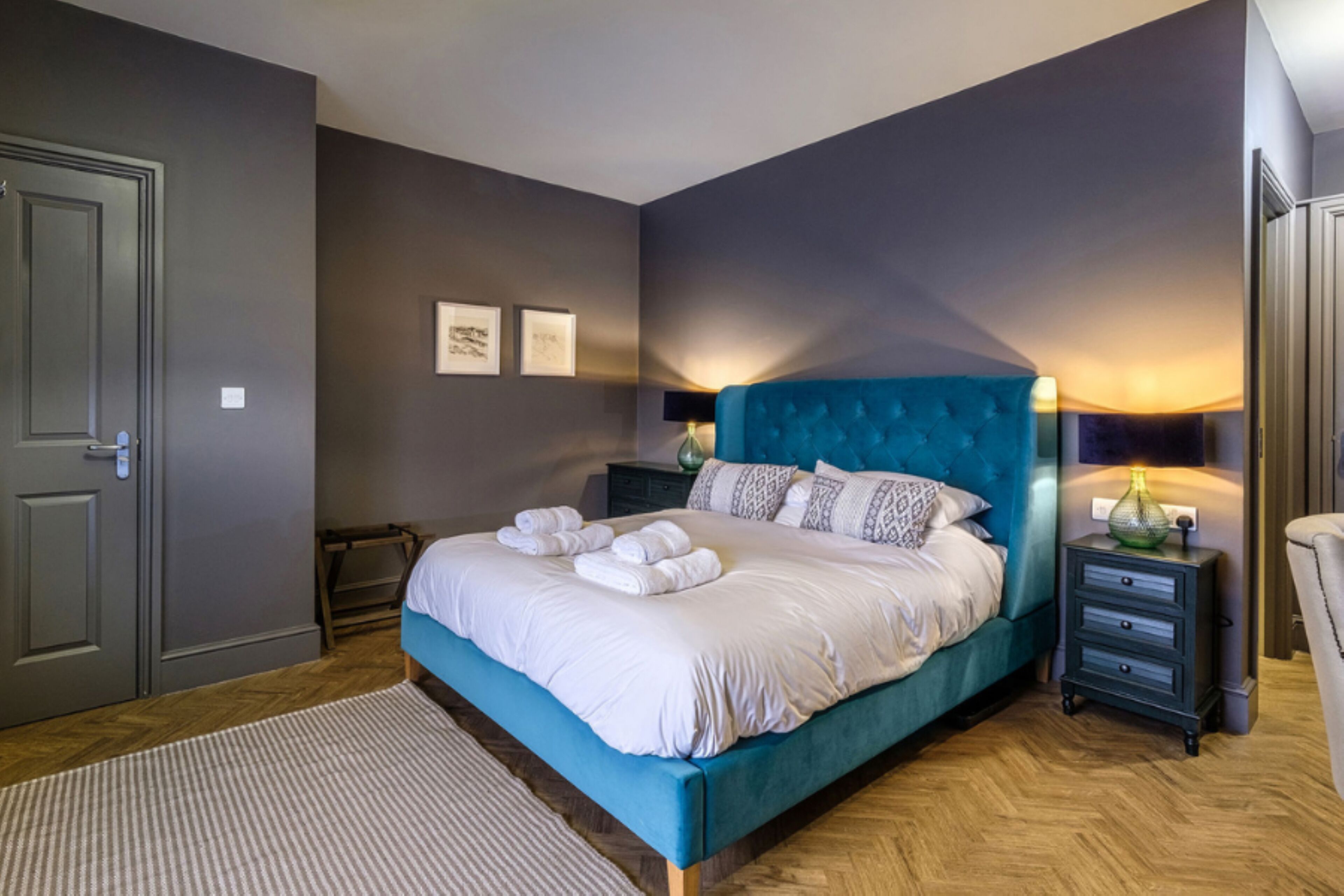 Un dormitorio moderno con una cama grande, una mesita de noche, una lámpara y una puerta.