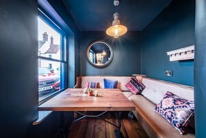 Una habitación acogedora con una mesa de madera, un espejo redondo y un banco con cojines.