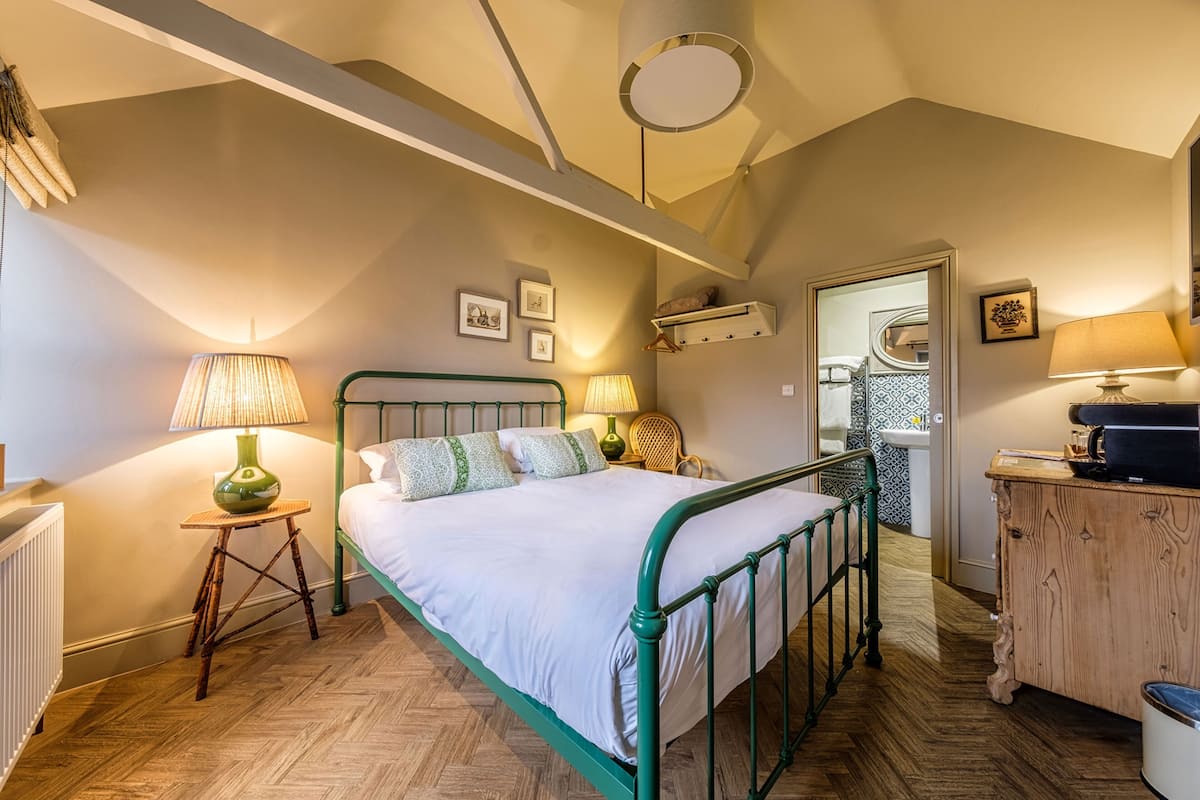Un dormitorio con estructura de cama de metal, cómoda de madera y radiador.
