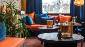 A cozy living room with a sofa, a coffee table, and a large window with curtains. - Vauldalen Fjellhotell (Roros)