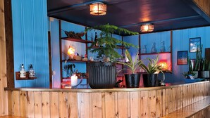 A wooden reception area with a curved counter, potted plants, and hanging baskets. - Vauldalen Fjellhotell (Roros)