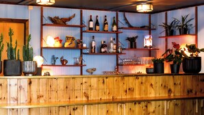 A wooden bar area with shelves displaying bottles, glasses, and plants. - Vauldalen Fjellhotell (Roros)