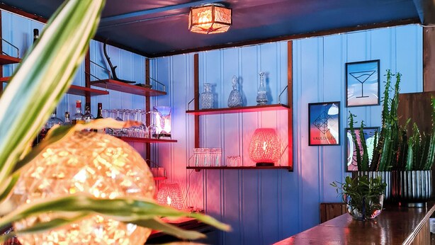 A bar area with a wooden counter, shelves with bottles, and framed pictures on the wall. - Vauldalen Fjellhotell (Roros)