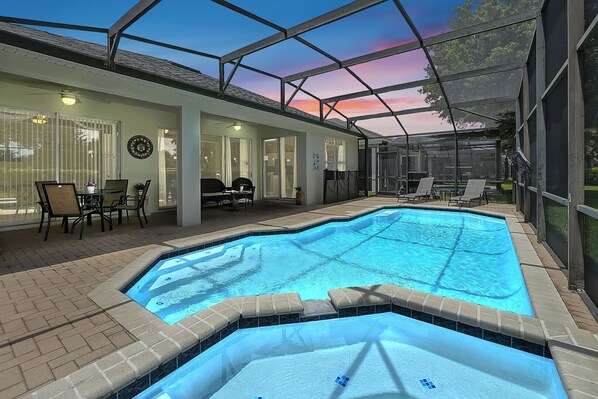 Una piscina interior con techo de vidrio, rodeada de sillas de descanso y una zona de patio.