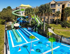 Enjoy water slides and a central pool surrounded by lush greenery and palm trees.