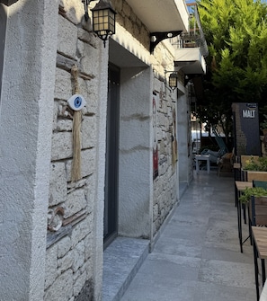A stone building with a sign indicating a Malt hotel, outdoor seating, and a staircase leading to an upper level. - Cielo Limon Alaçatı - Adults Only (Cesme)