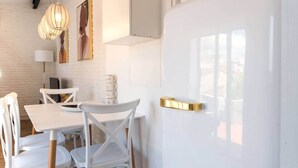 A modern dining area with white furniture, pendant lighting, and a view of the outdoors. - Blanda Family Apartment (Blanes)