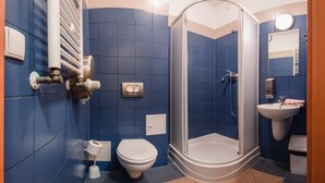 Een badkamer met douche, toilet, wastafel en handdoekrek.