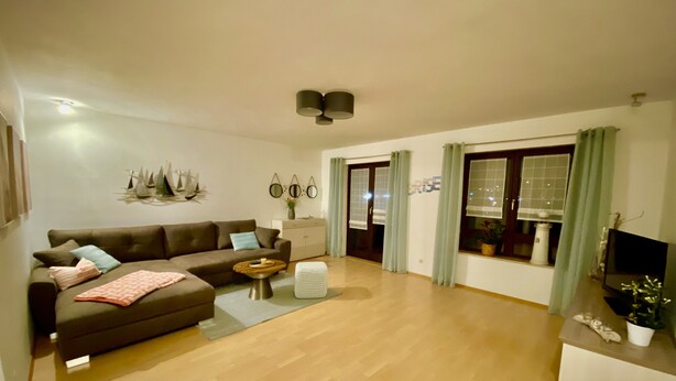 A living room with a brown sofa, a coffee table, and a TV on a stand. - Vacation apartment Pier 7 - directly on the lake! (Bitterfeld-Wolfen)