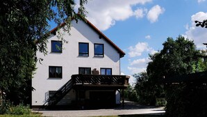 A two-story house with a balcony, a staircase, and a driveway. - Vacation apartment Pier 7 - directly on the lake! (Bitterfeld-Wolfen)