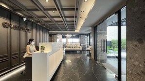 Un moderno vestíbulo de hotel con mostrador de recepción, zona de estar y ventanas amplias con vistas al exterior.