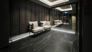 Un vestíbulo moderno con paneles de madera oscura, suelo de mármol y asientos contemporáneos.