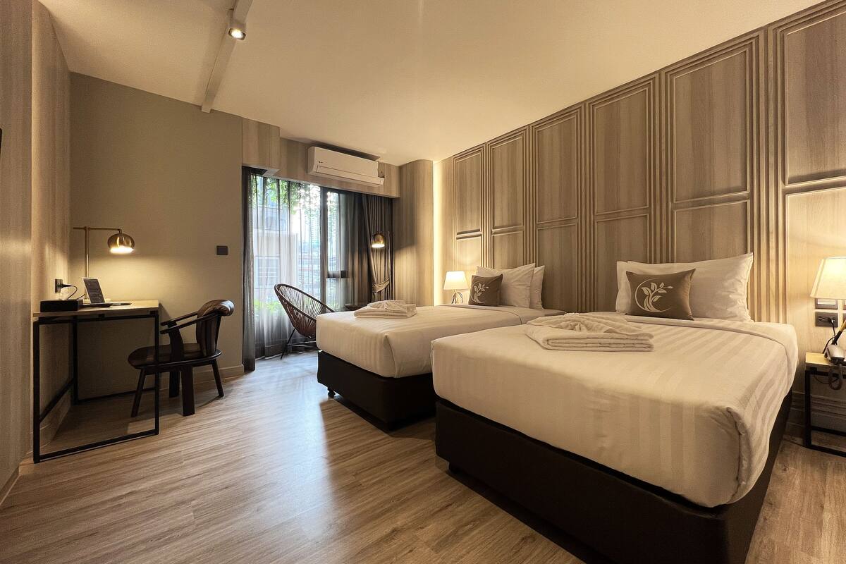 Habitación de hotel con dos camas, un escritorio y una silla.