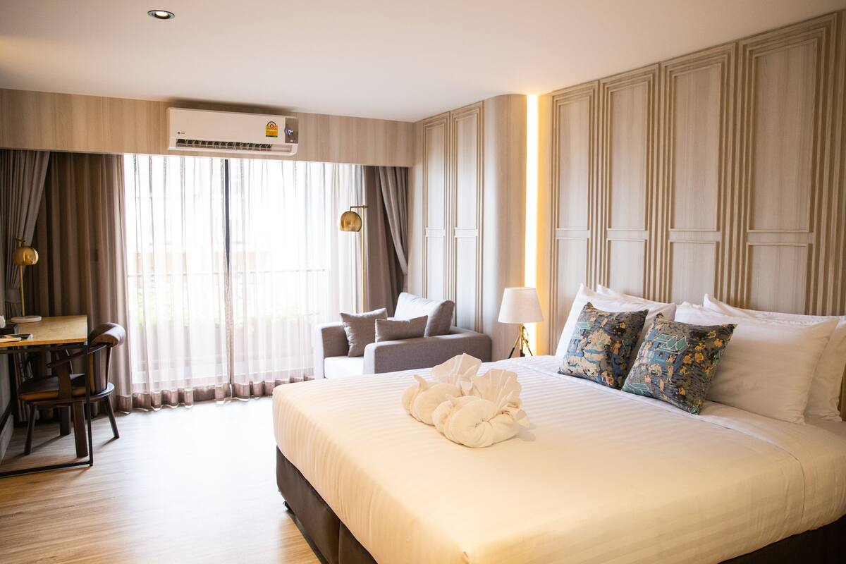 Habitación de hotel con una cama grande, un escritorio con una silla, un sofá y una lámpara.