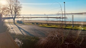 A park with a paved walkway, benches, and a wooden pier extending into a calm body of water.