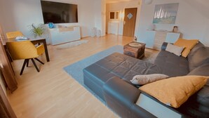 A modern living room with a sofa, a dining table, and a TV.