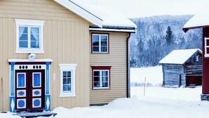Un bâtiment à deux étages, doté d’une façade marron et d’une porte rouge, entouré de neige.