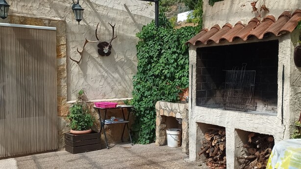 A covered outdoor area with a grill, potted plants, and a rustic stone wall. - RURAL HOUSE IDEAL FOR CELEBRATIONS, LARGE LIVING ROOM, BARBECUE, 18 PEOPLE (Valdemoro-Sierra)